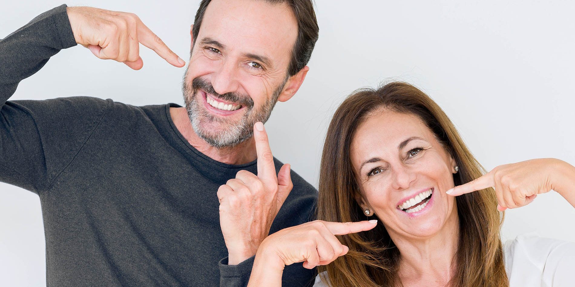 Beautiful middle age couple in love over isolated background smiling confident showing and pointing with fingers teeth and mouth. Health concept.