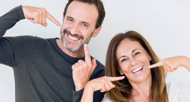 Beautiful middle age couple in love over isolated background smiling confident showing and pointing with fingers teeth and mouth. Health concept.